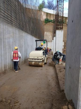 Rodillo compactador trabajando sobre un relleno junto a un muro